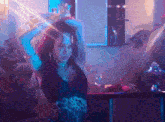 a woman is dancing in a dark room with a purple light behind her