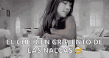 a woman in a red sweater is standing in a room with a sign that says el che bien gripiento de las nalgas