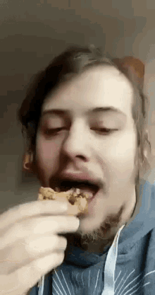a man with a beard is eating a cookie with his eyes closed