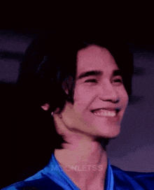 a close up of a man wearing a blue shirt and a ring on his finger .