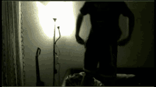 a man in a black shirt is standing in front of a lamp in a dark room