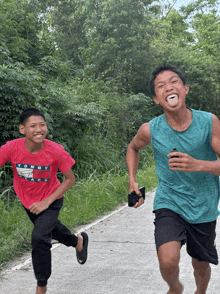 two boys are running down a road one is wearing a tommy jeans shirt