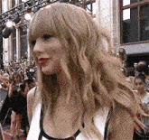 a woman with blonde hair and bangs stands in front of a crowd