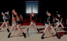 a group of young women are sitting on stools in a dark room