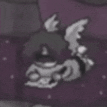 a cartoon character with wings is laying on a purple blanket .