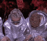 two people in space suits are sitting in front of a sign that says ' a ' on it