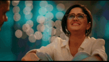 a woman wearing glasses and a white shirt smiles at a man