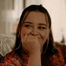 a woman covering her mouth with her hand and smiling at the camera