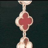 a close up of a pendant with a red clover shaped pendant on a black background .