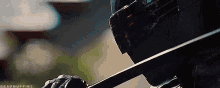 a close up of a person wearing a helmet and gloves holding a sword .