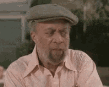 an elderly man with a beard and hat is sitting at a table .
