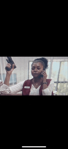 a woman is holding a gun in her hand while talking on a cell phone .