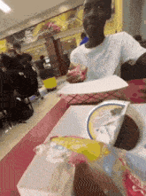 a person sitting at a table with a container of ice cream