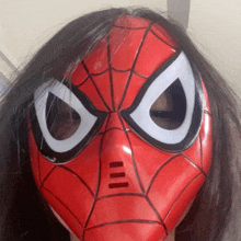 a woman wearing a red and black spider man mask with white eyes
