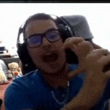 a man wearing headphones and glasses is making a heart shape with his hand .