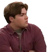 a man in a purple shirt with his arms crossed looks to the side