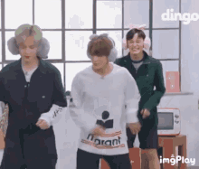 a group of young men are dancing in a room while wearing ear muffs .