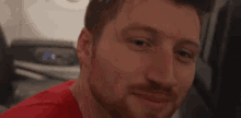 a man in a red shirt is smiling in front of a washing machine