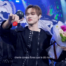 a man in a black jacket is holding a bouquet of flowers