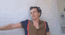 a man is laying on the floor in front of a white brick wall .