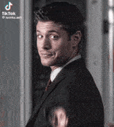 a man in a suit and tie is making a funny face and waving .