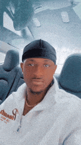 a man in a car wearing a white sweatshirt that says ' denim ' on it