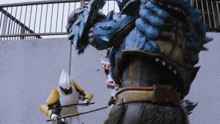 a man in a white and yellow costume is fighting a monster