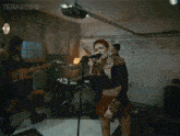 a woman is singing into a microphone in a garage while a band plays behind her .
