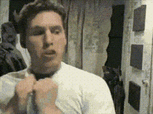 a man in a white shirt is adjusting his tie in a room