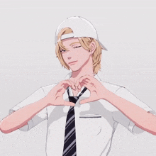 a man in a white hat and tie making a heart with his hands