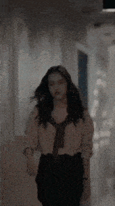 a woman is walking down a hallway wearing a tie and a shirt .