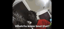 a man in a red shirt is talking into a microphone with the words " whatchu know bout that " below him