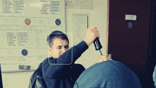 a man is holding a screwdriver in front of a white board that says 11/12