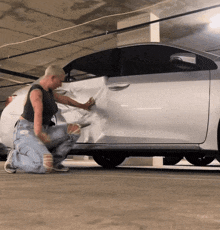 a woman is wrapping a silver car in plastic