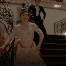 a woman in a white dress is walking down a set of stairs next to a woman in a black dress