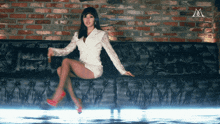 a woman is sitting on a black couch with a brick wall behind her