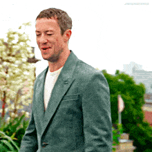 a man in a green suit and white shirt is standing in front of trees and a sign that says joequinngrayes