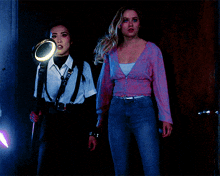 two women standing next to each other with one holding a magnifying glass and the other holding a light