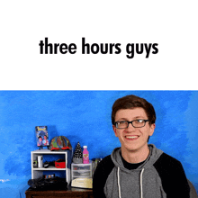 a young man wearing glasses is smiling in front of a blue wall with the words three hours guys above him