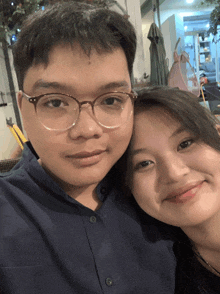 a man wearing glasses and a woman are posing for a picture