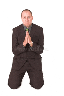a man in a suit is kneeling down with his hands together