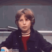 a young boy is sitting in front of a blackboard and the word momento is above him