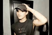 a young man wearing a baseball cap and a black shirt is standing in front of a mirror .