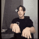 a young man is sitting at a desk with his hands outstretched and making a funny face .