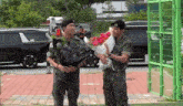 a man in a military uniform holds a bouquet of flowers while standing next to another man