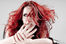 a woman with red hair is biting her nails