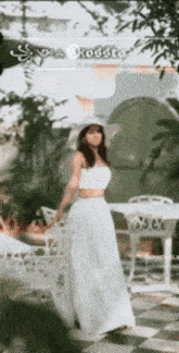 a woman in a white dress is standing in front of a checkered floor .
