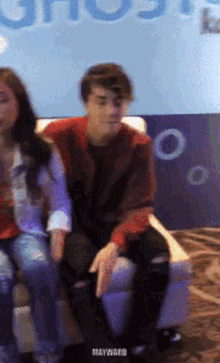 a man and a woman are sitting in front of a sign that says ghost on it