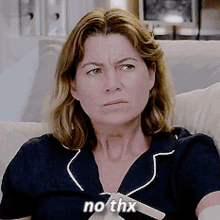 a woman is sitting on a couch with the words no thx written on her shirt