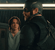 a man in a superhero costume stands next to a man in a scrub top